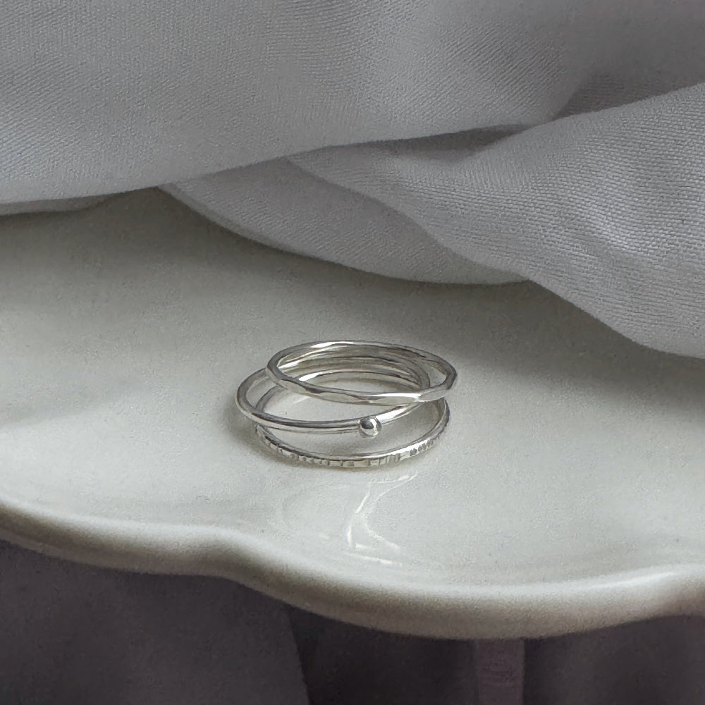 Three silver rings on a white surface with gray fabric in the background
