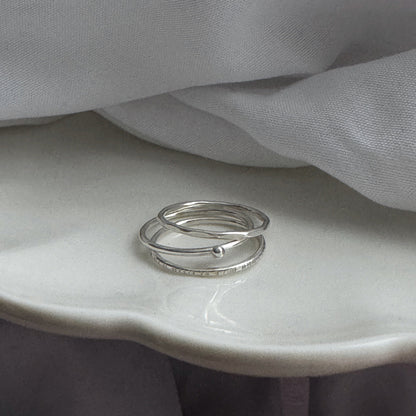 Three silver rings on a white surface with gray fabric in the background
