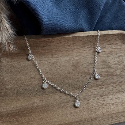 Silver necklace with small star charms on a wooden surface