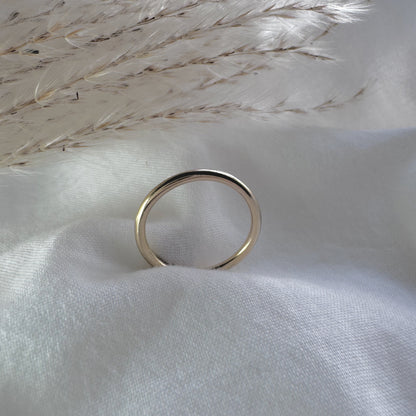 a simple gold plain band ring on a white fabric background
