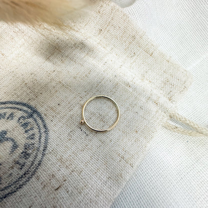 A 9ct gold ball stacking ring with a small ball on top, placed on a white textured surface.
