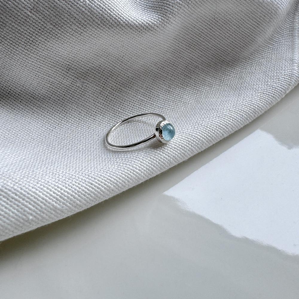 Aquamarine in a silver setting on top of a thin silver band