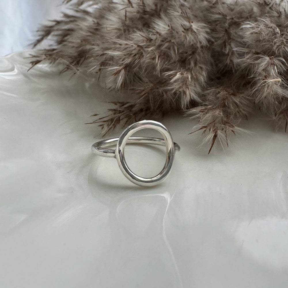 Silver ring on a white surface with dried pampas grass