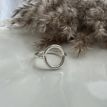 Silver ring on a white surface with dried pampas grass