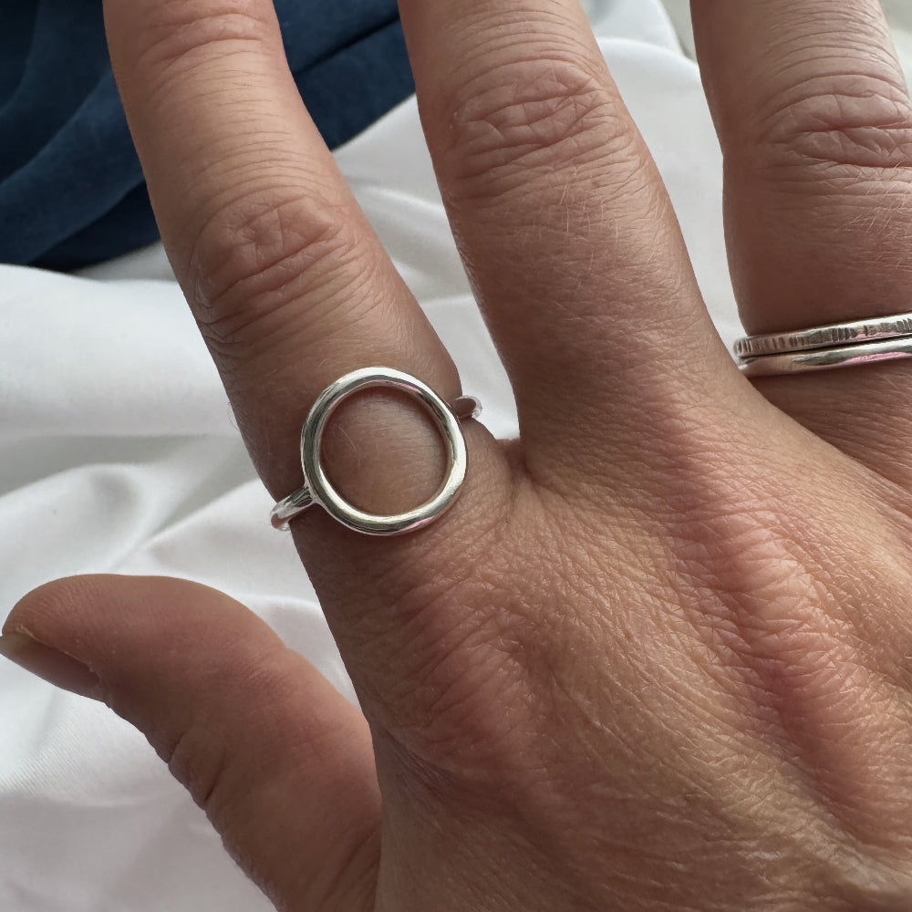 Close-up of a hand wearing a silver circle ring on a white background