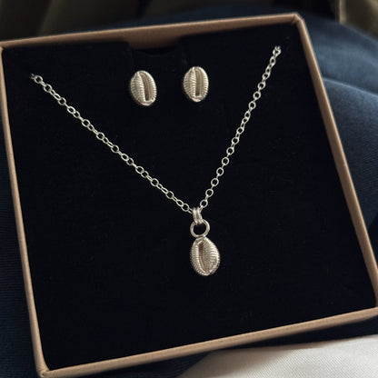 Silver necklace and earrings set in a box on a dark surface