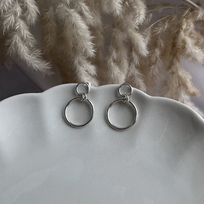 Silver hoop earrings on a mannequin bust with dried pampas grass in the background