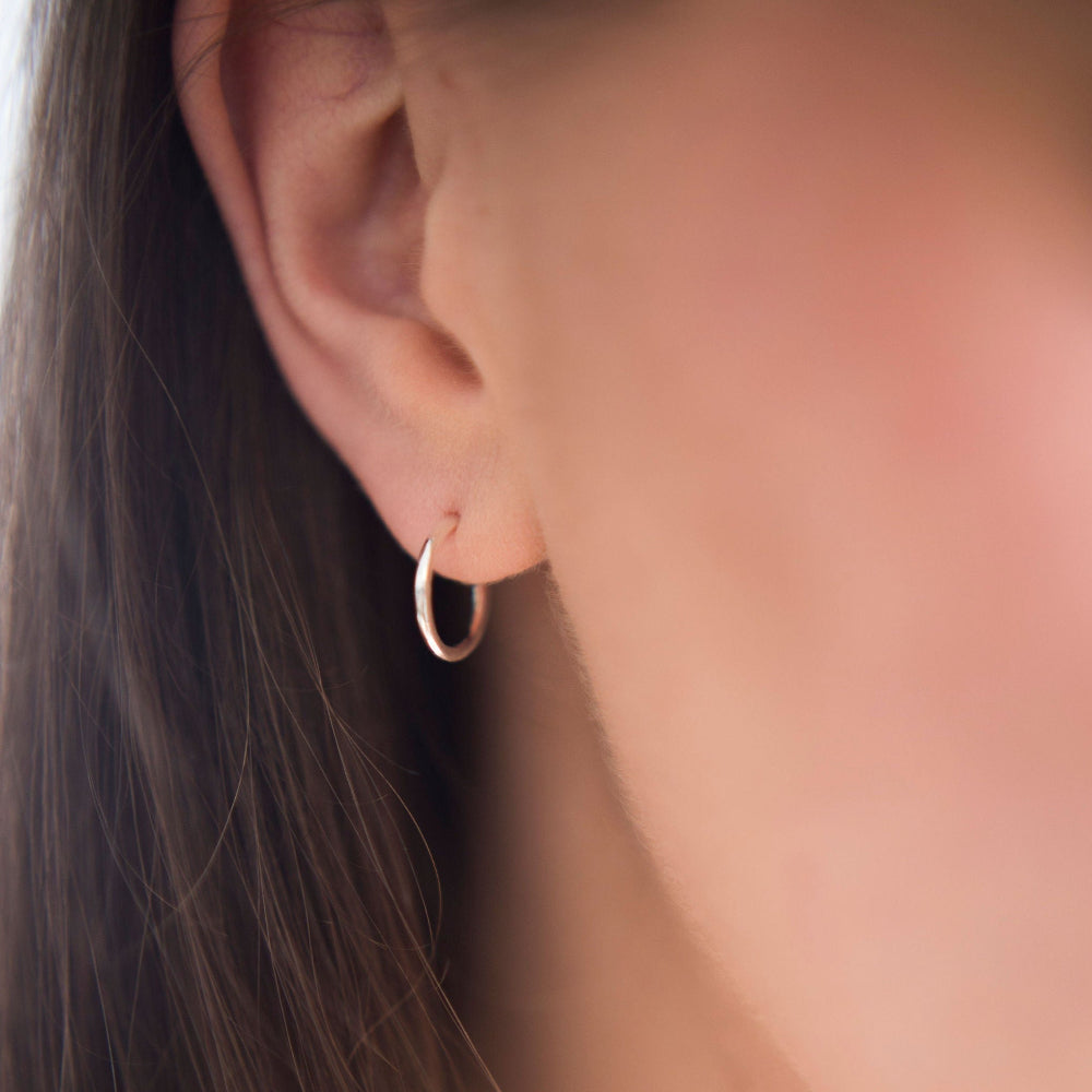 Small Silver hoop earrings being worn by a lady with long dark hair