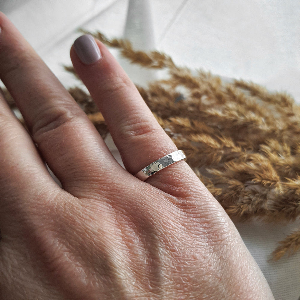 a 3mm wide hammered silver ring being worn on the little finger