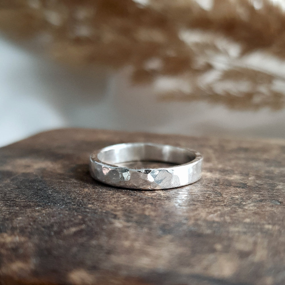 a hammered silver ring thats 3mm wide on wood