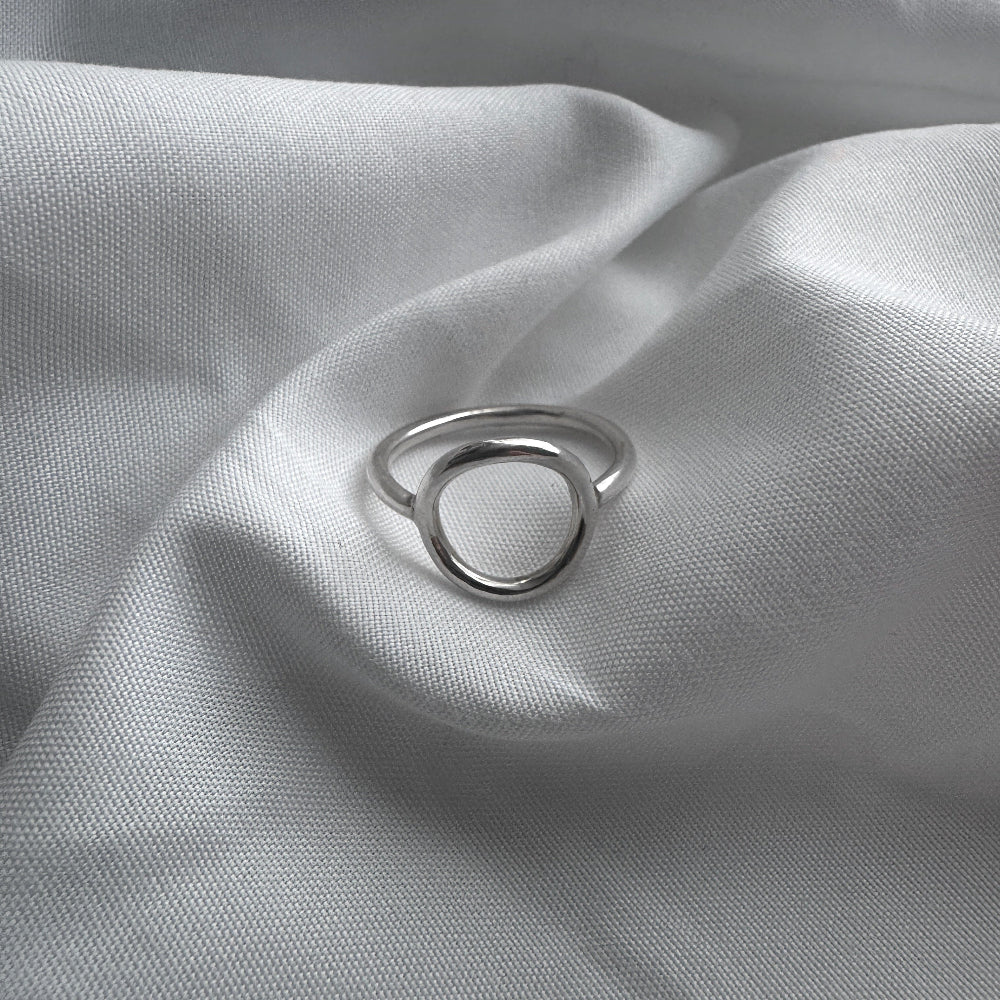 Silver circle ring on a textured gray fabric surface