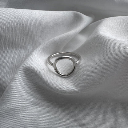 Silver circle ring on a textured gray fabric surface