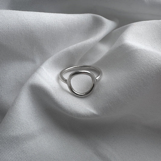 Silver circle ring on a textured gray fabric surface