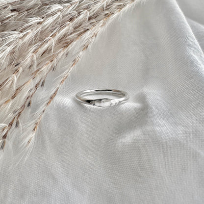 silver hammered mini signet ring on a white fabric background with dried grass