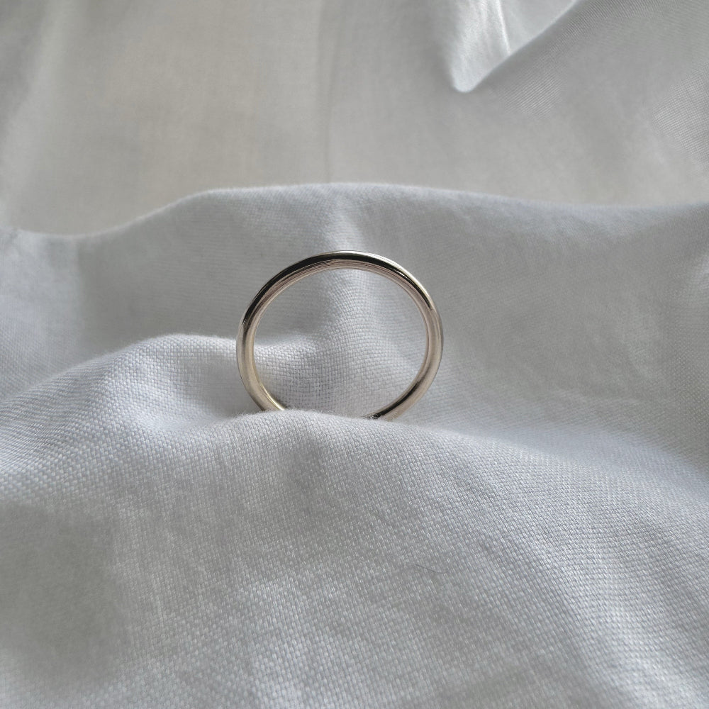 a simple gold plain band ring on a white fabric background