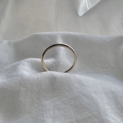 a simple gold plain band ring on a white fabric background