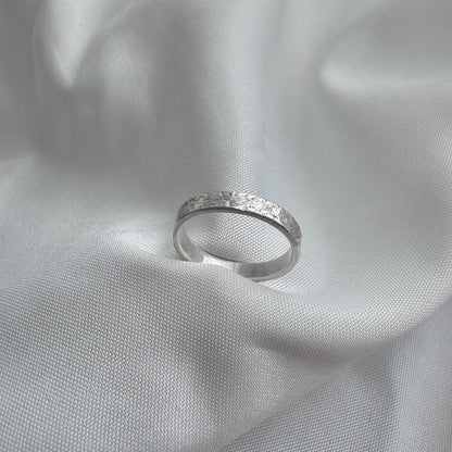 Silver ring with sand texture on a light gray fabric background