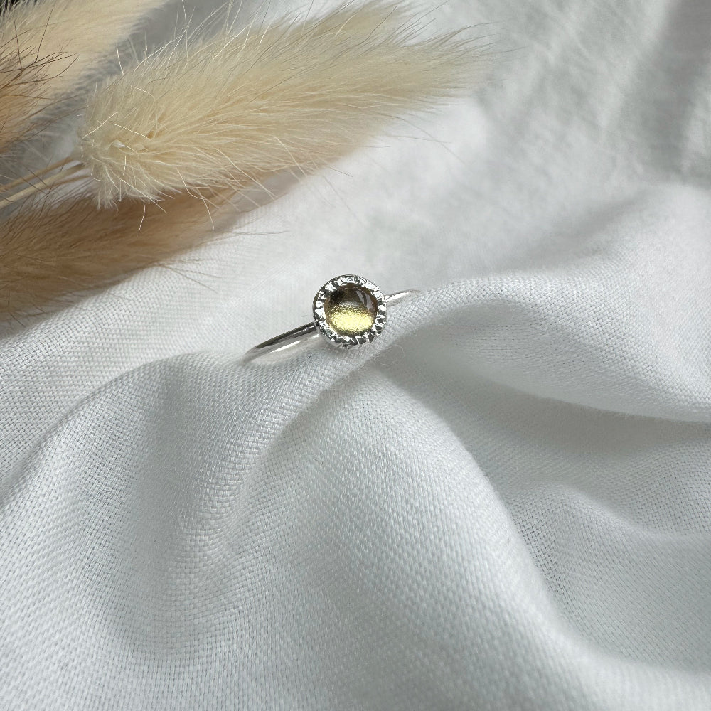 5mm citrine set in a rustic setting on a thin silver band on white fabric