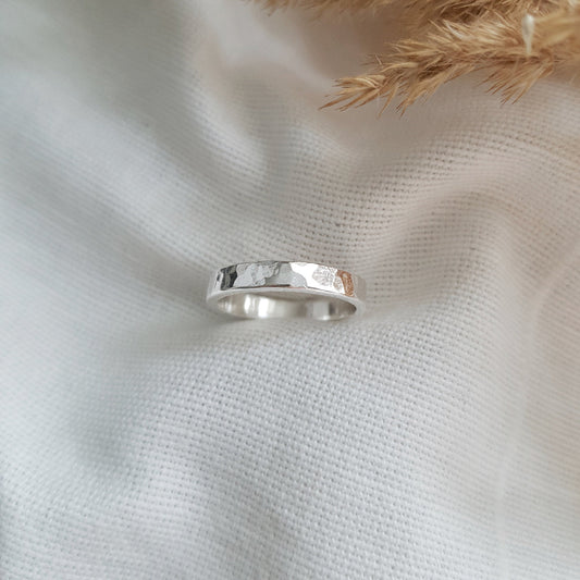 a chunky silver hammered ring on white fabric