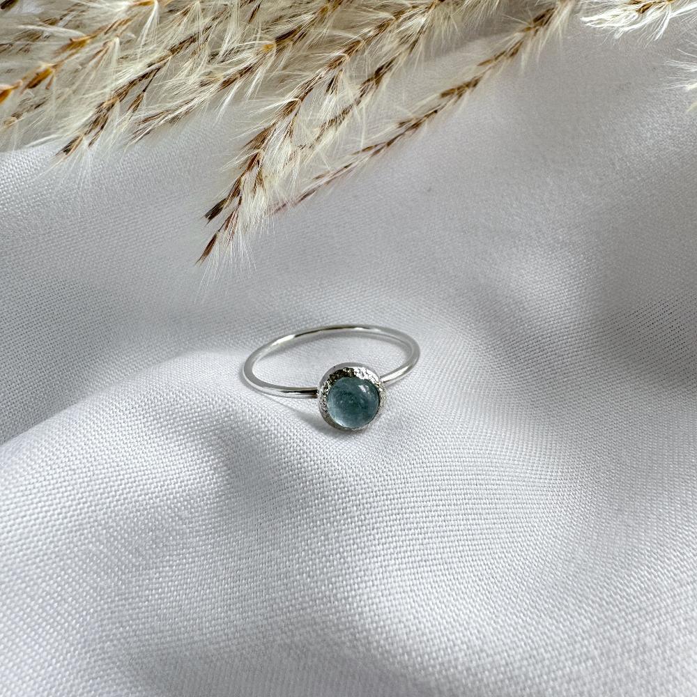 Round pale blue aquamarine stone set on top  of a dainty silver ring