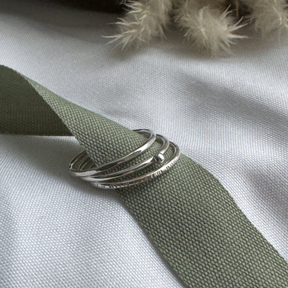 Three silver rings on a green fabric with a neutral background