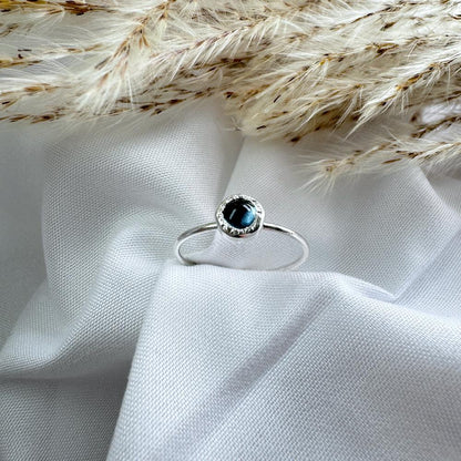 A blue topaz in in organic setting set on top on a thin silver band