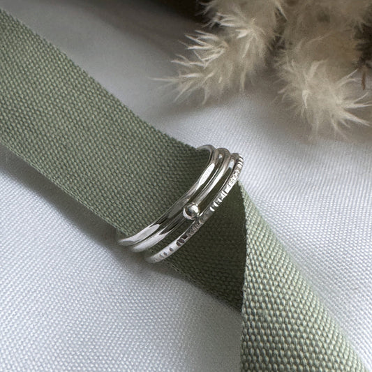 Silver stacking rings on a green fabric background