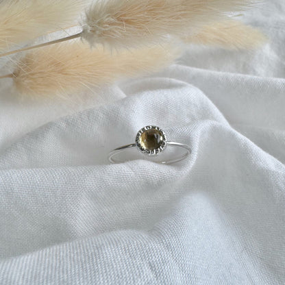 5mm citrine set in a rustic setting on a thin silver band in white fabric