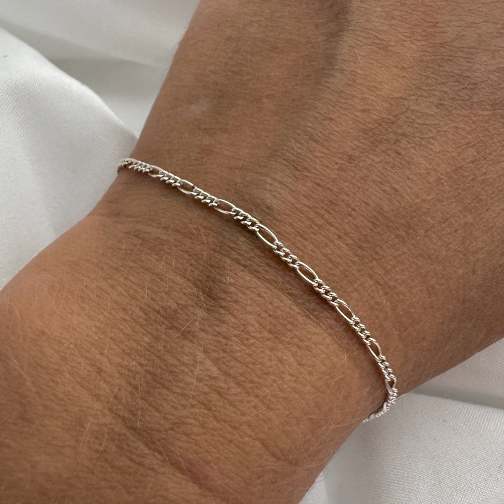 Silver bracelet on a wrist with a plain background