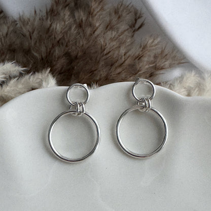 Pair of silver hoop earrings on a white surface with a fur background