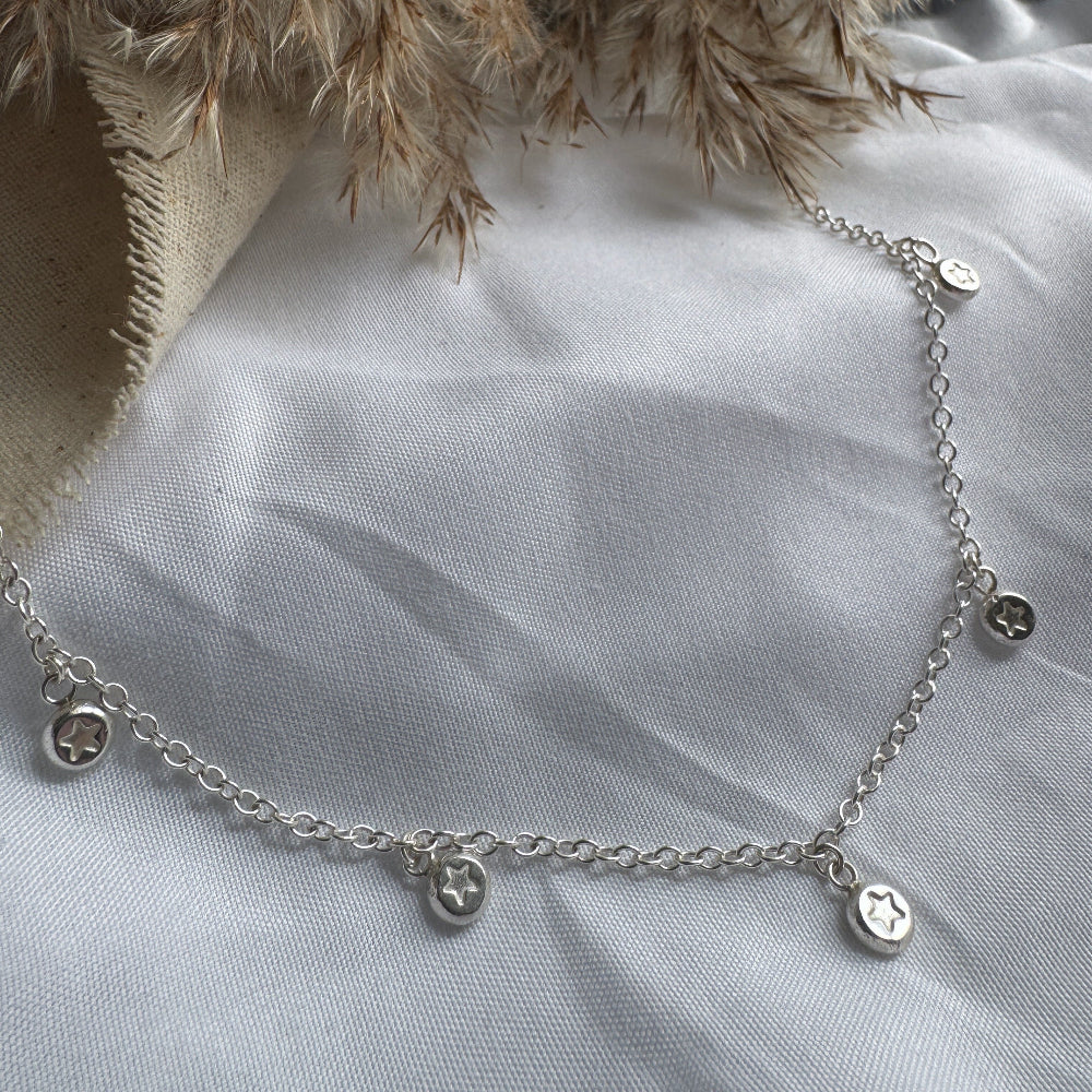Silver necklace with star charms on a light fabric surface