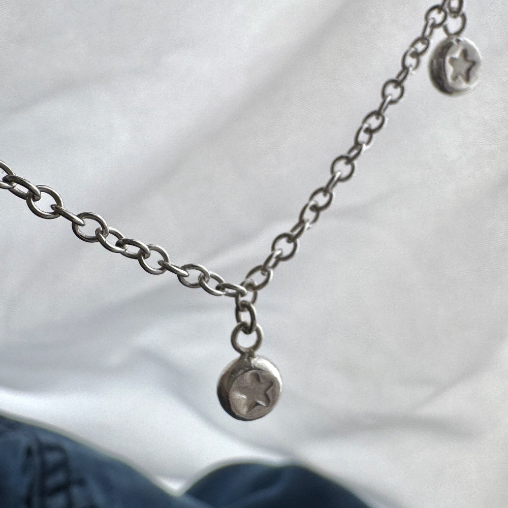 Silver necklace with circular pendants on a white fabric background