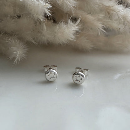 Silver star earrings on a white surface with a fluffy white background