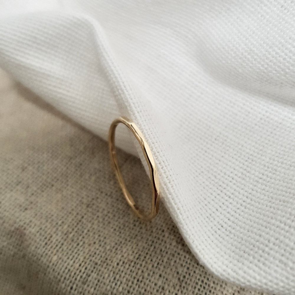 A 9ct gold hexagonal stacking ring on a a cream textured fabric