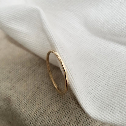 A 9ct gold hexagonal stacking ring on a a cream textured fabric