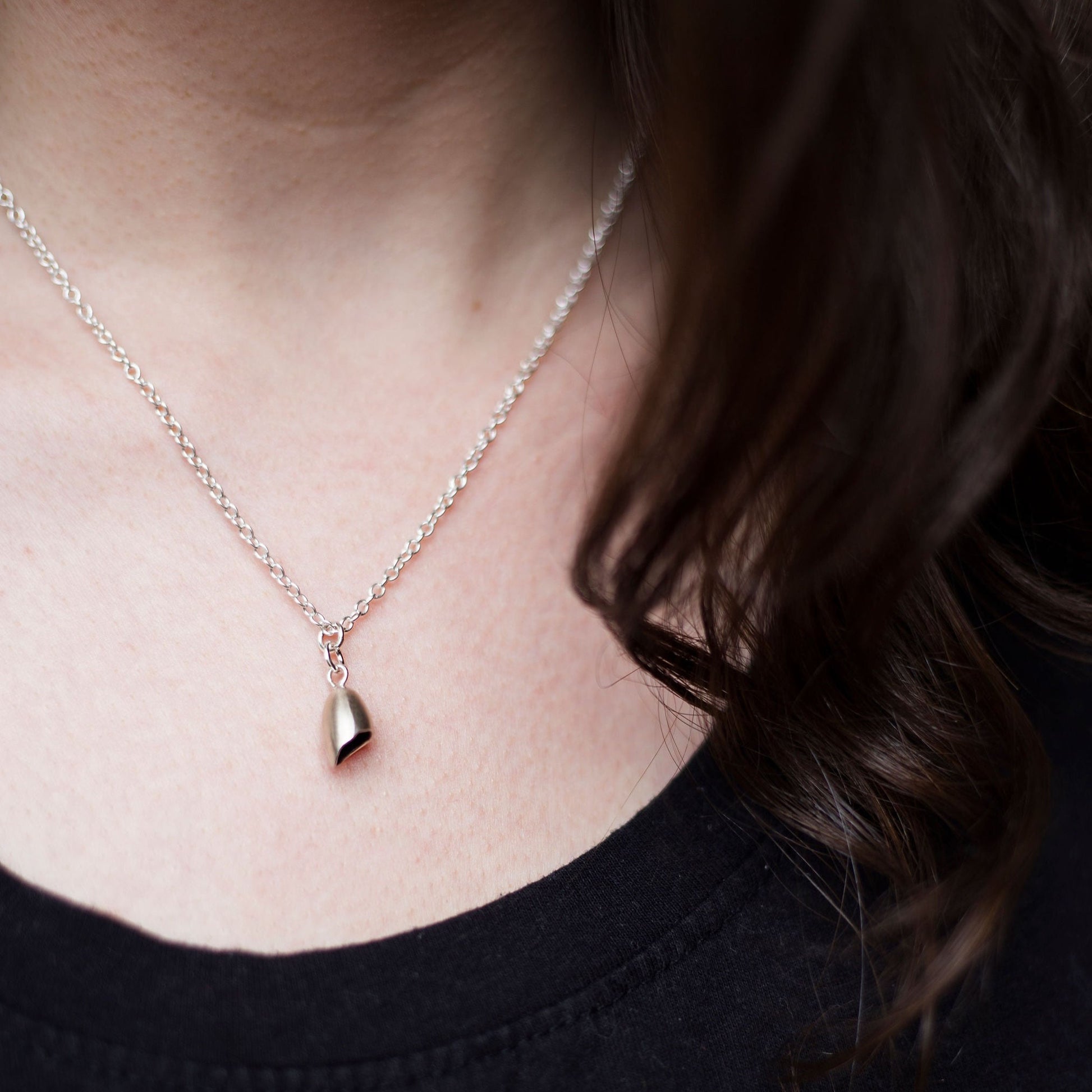 sterling silver pod necklace with dark inside on chain being worn with a black t-shirt