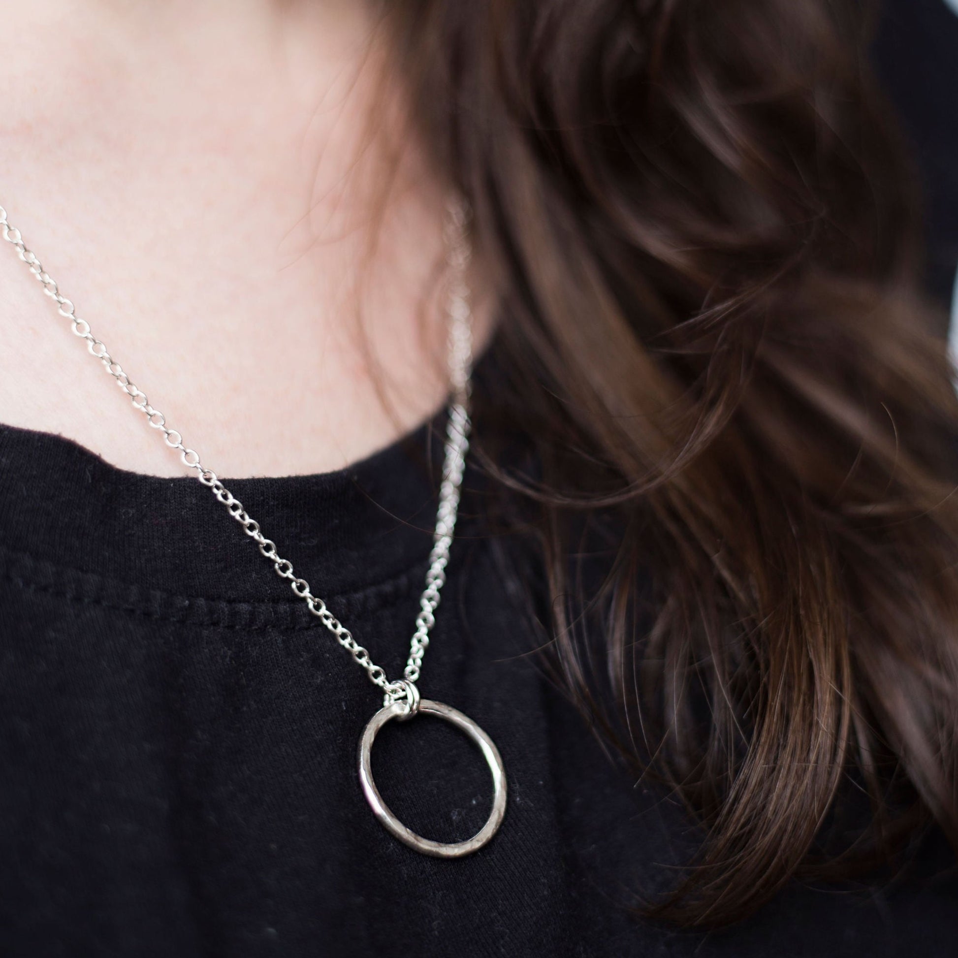 Hammered Silver Circle Necklace worn with a black t-shirt , handmade by Anna Calvert Jewellery