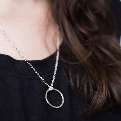 Hammered Silver Circle Necklace worn over a black t-shirt  by a lady with long dark hair