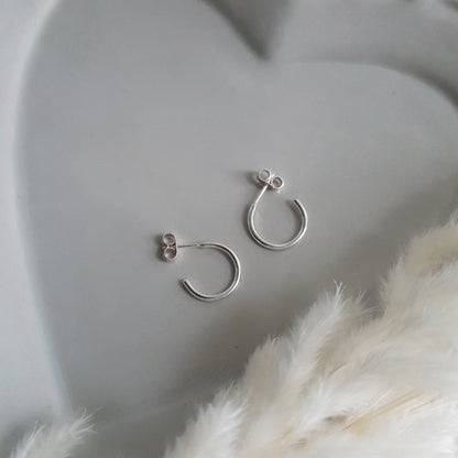 small silver pen hoop earrings on a pale grey ceramic plate