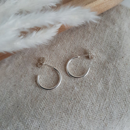 silver open hoop earrings on a cream textured fabric