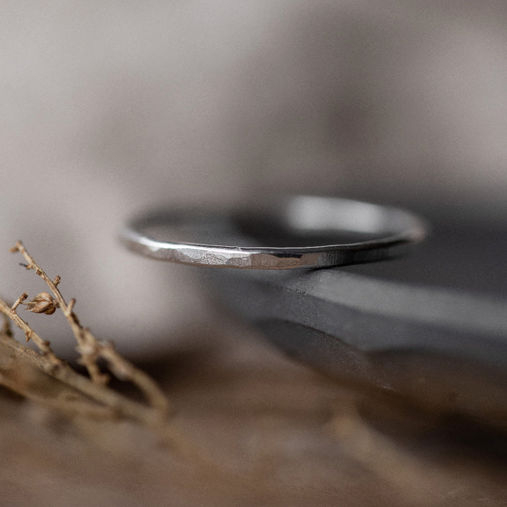 A dainty Textured Silver Stacking Ring  on the edge of a dish on a blurred background