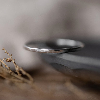 A dainty Textured Silver Stacking Ring  on the edge of a dish on a blurred background