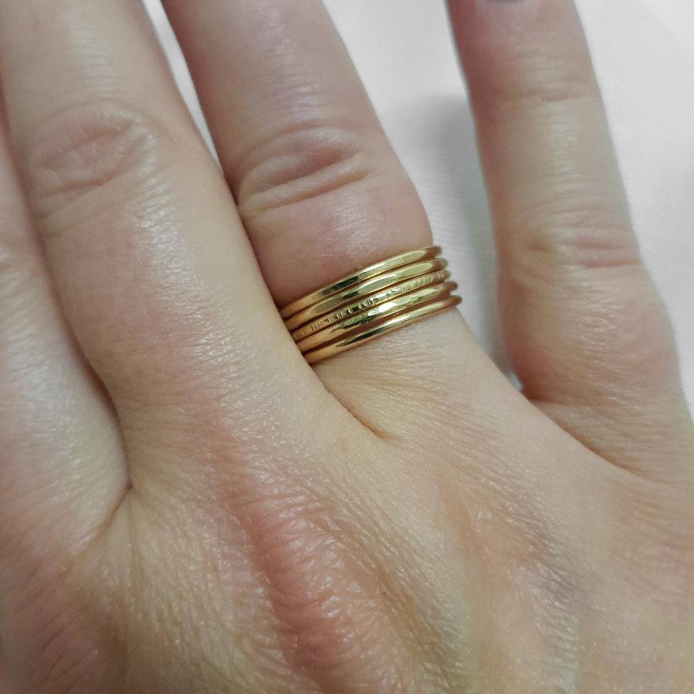 Five Gold Stacking rings being worn together on the fourth finger of a hand