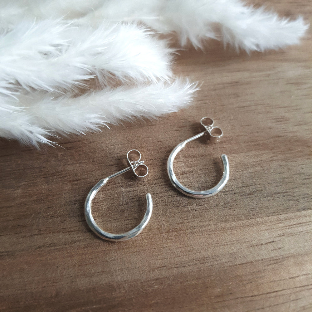Small hammered silver hoops on a wooden background 
