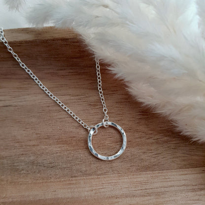 Silver circle necklace on a wooden background