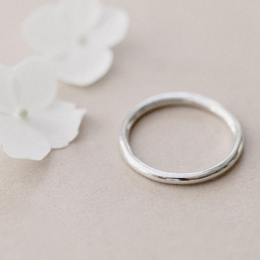 A simple plain silver infinity ring placed on a beige background.