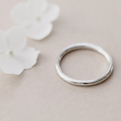 A simple plain silver infinity ring placed on a beige background.
