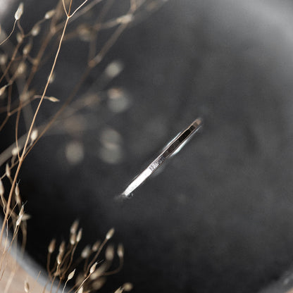 a dainty Flat Textured Silver Stacking Ring on a dark grey background