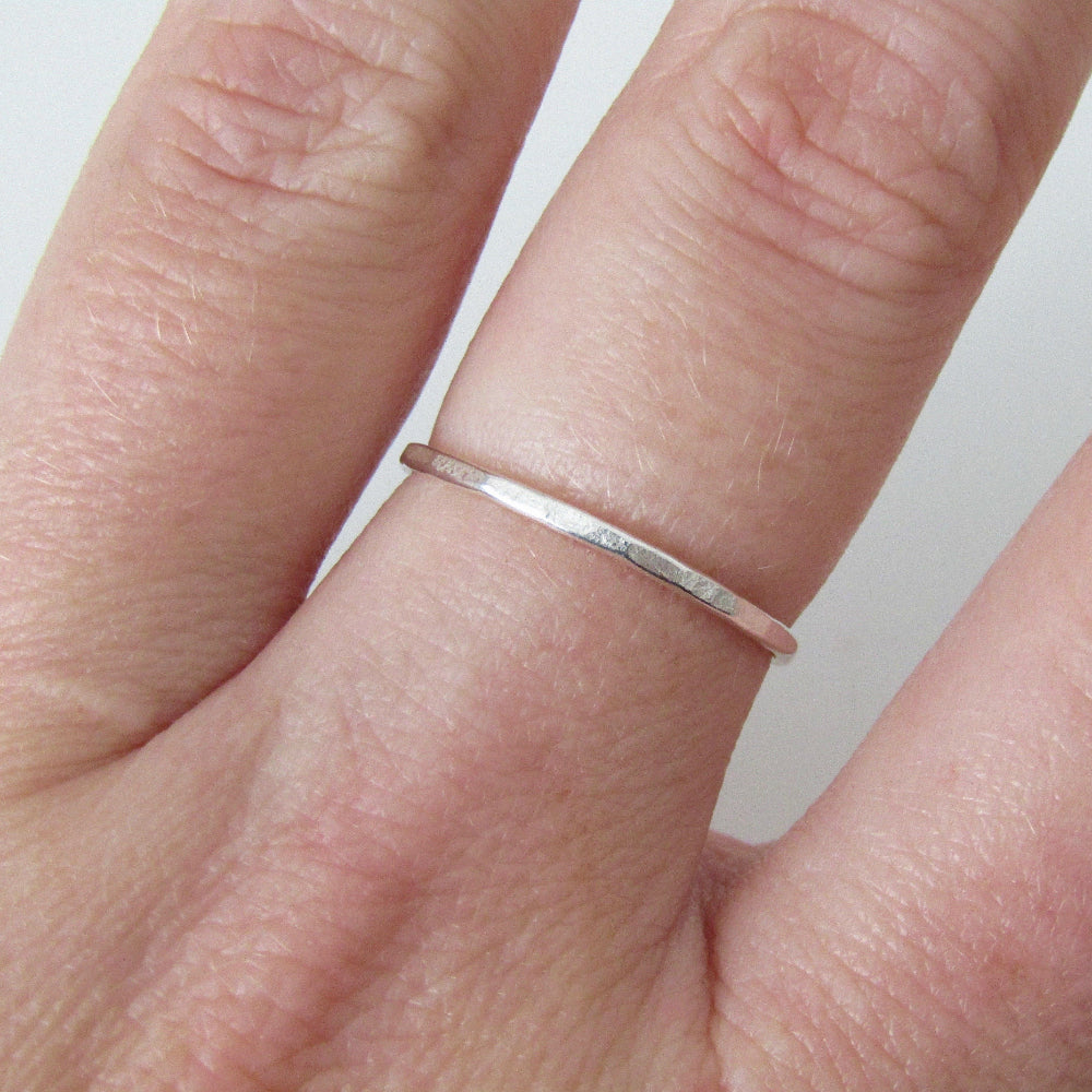 Flat Textured Silver Stacking Ring  worn on the middle finger of a hand