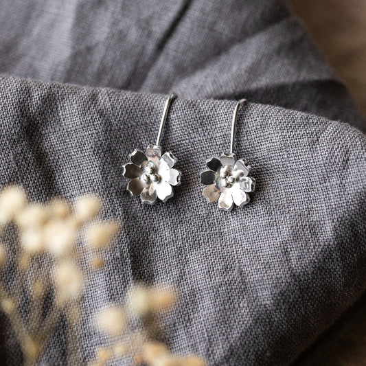 Dangly Silver Flower Hook Earrings, on grey fabric